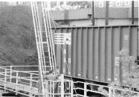 climbing the tower, the worker directs a water cannon to flush the coal from the coal car through the tracks depositing in the pit